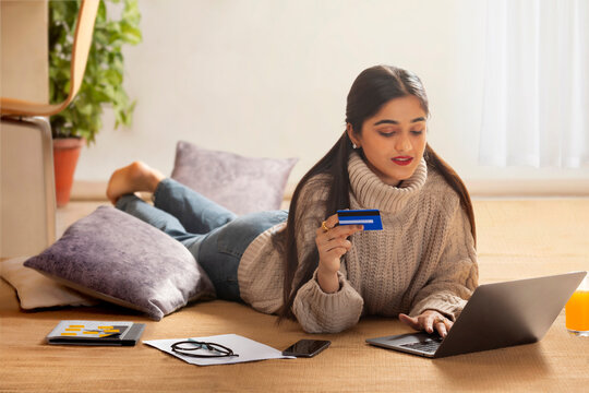 Smart young girl shopping online through laptop using debit card