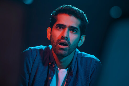 Portrait of a shocked and surprised man while watching horror movie in the movie theater