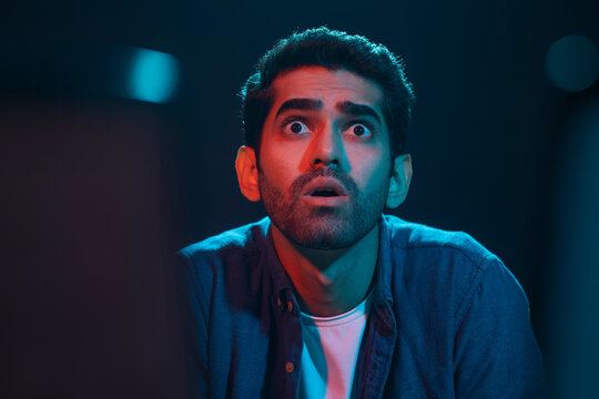 Portrait of a shocked and surprised man while watching horror movie in the movie theater
