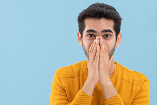 Portrait of a surprised  young man looking at the camera with covering his mouth with hands