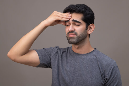 Portrait of a young man suffering from headache with hand on forehead 