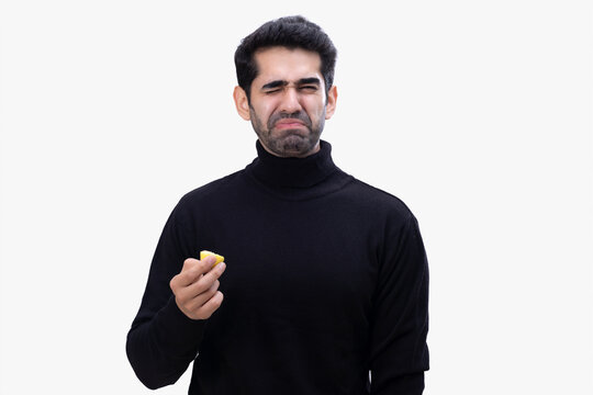 Expression of a young man after sucking sour lemon