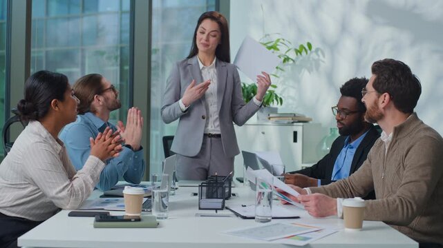 Caucasian leader woman boss with document talking to business team applauding at office meeting. Successful businesswoman talk to managers colleagues applause at conference briefing good presentation