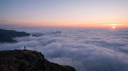 Obraz premium Person standing on mountain peak above clouds. Hiker watching sunset over valley landscape.