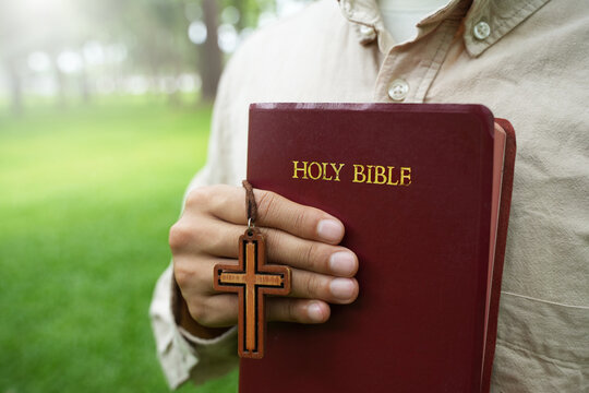 The concept of reading the Bible and praying to God for blessings, living peacefully in nature and spending time with God, with a hand holding a Bible.