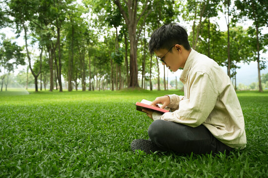 The concept of reading the Bible and praying to God for blessings, living peacefully in nature and spending time with God, with a hand holding a Bible.