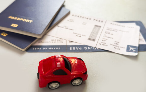 toy car on table with boarding pass and passport, travel preparation top-down view in red and blue setting, commercial editorial use case for vacation planning.