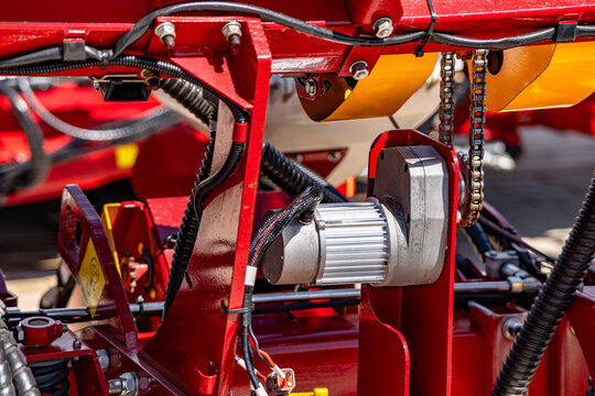 Agricultural seed drill electric drive motor and chain transmission unit. Modern farming planter component closeup view with sprocket mechanism and smart technical electronic details for tractor.