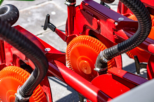 Agricultural seeder precision vacuum seed meter disk mechanism. Modern farming planter row unit component closeup view with corrugated suction hoses and technical engineering vehicle details.
