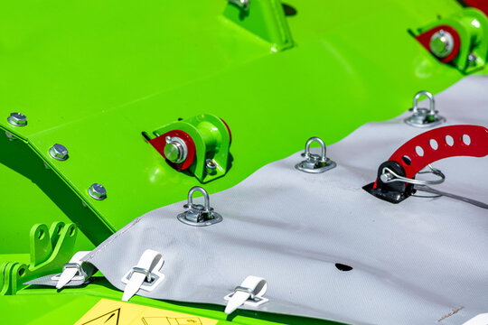Agricultural disc mower protective canvas cover and fasteners closeup. Modern farming forage harvester machine mechanism component with linch pins and industrial cultivation technical details.