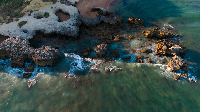 Rock formations along a coastline waves crashing against the rocks, in beach and ocean, with rock formations, waves, ocean water, with rocks, sand, water texture. Praia dos Aveiros Portugal