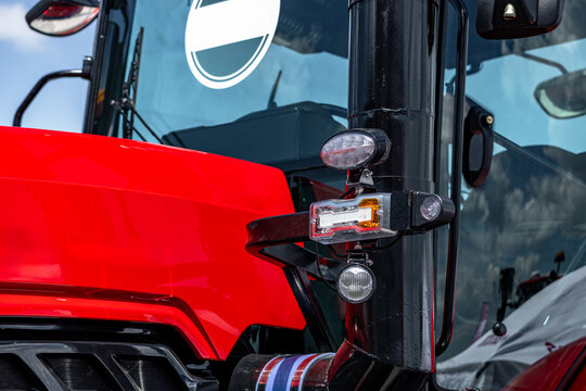 Agricultural tractor cabin front pillar with led position lights. Modern farm machinery engine hood closeup view with glass windshield and industrial transport vehicle technical details.