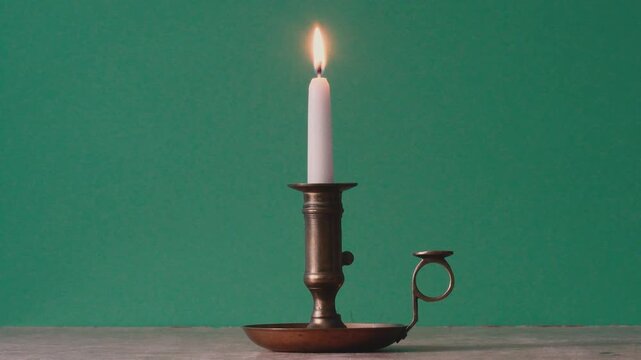 place a burning candle on the table and extinguish it in an antique candlestick