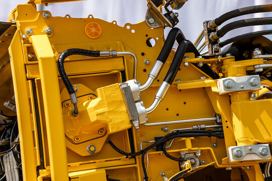 Agricultural sugar beet harvester hydraulic motor with valve block. Modern farming machinery fluid power transmission component on yellow frame with high pressure hoses and technical details.