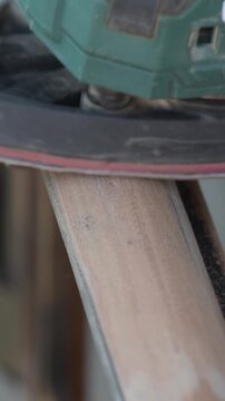 Removing small part of a wooden surface from old paint with a sander close up