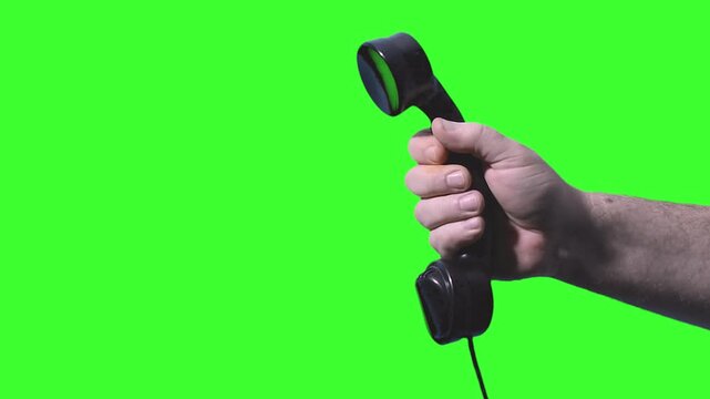 Person reaching out with old phone receiver in a green background setup - chroma key