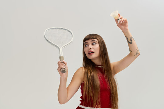 Stylish young woman channels retro vibes with badminton racket in studio