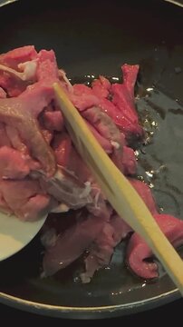 Frying meat pieces in hot oil in a frying pan on a stovetop for tasty cooking