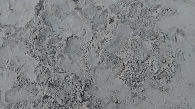 snow in the snow,Gray sand shows deep, worn footprints. Texture reveals recent footsteps, gentle pressure. Natural, quiet scene invites stillness or memory. Perfect backdrop for travel, adventure, 