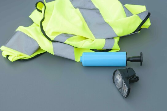 Safety gear for cycling including a reflective vest, pump, and bicycle light on a flat surface