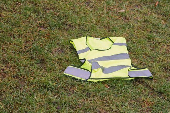 Safety vest left on grass in a public park during late afternoon hours