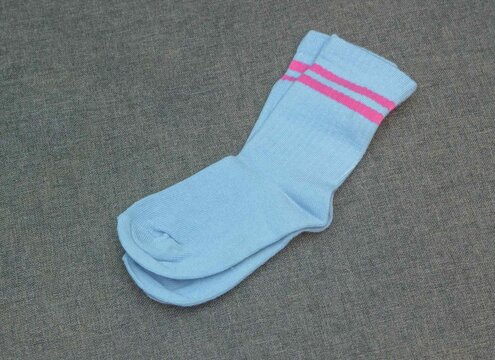 Light blue socks with pink stripes placed on a gray surface for a simple display of color and design