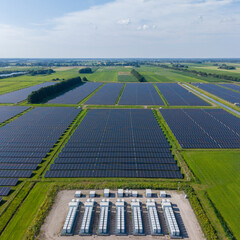 Aerial view of a large-scale solar farm featuring extensive rows of photovoltaic panels and a battery energy storage system in the rural landscape of Wanneperveen, Overijssel, Netherlands. © Ewout Pahud