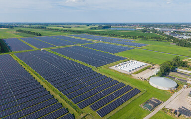 Aerial view of a large-scale solar farm featuring extensive rows of photovoltaic panels and a battery energy storage system in the rural landscape of Wanneperveen, Overijssel, Netherlands. © Ewout Pahud