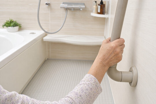 Senior hand holding bathroom grab bar for fall prevention