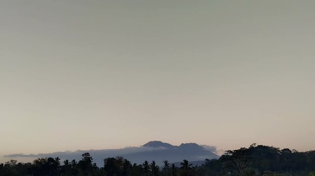Extreme wide eye level shot of a mountain peak silhouette with drifting clouds in the evening light.