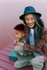 Fototapeta premium Playful grandmother and grandson fishing on a painted dock for poster and background use showing multigenerational bond and relaxed outdoor activity