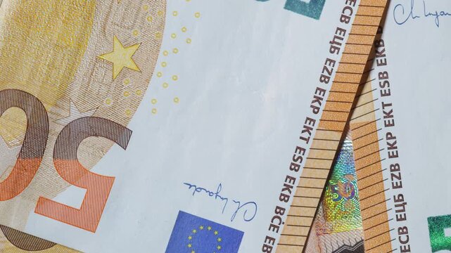 Fifty-euro banknotes on a tabletop; camera zooming out.