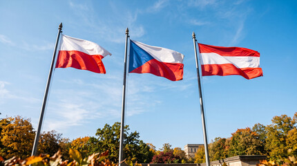 Fototapeta premium Three European national flags waving proudly against a clear blue sky