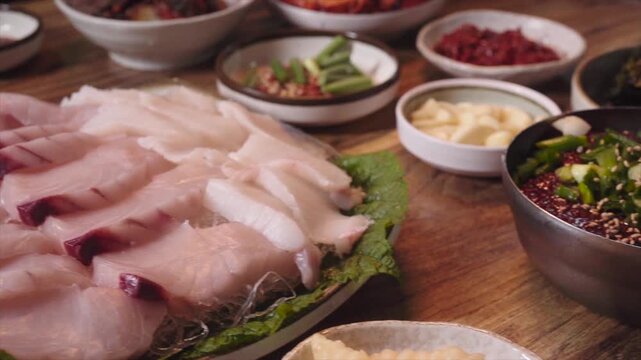Full table setup of Spanish mackerel sashimi with various traditional side dishes and sauces