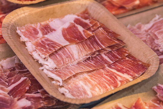 Raciones de jam&oacute;n ib&eacute;rico curado cortado en lonchas finas servido en un plato de cart&oacute;n