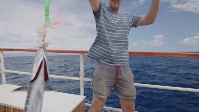 Sailor catches and holds the fish on the sailing boat