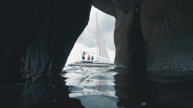 Sailing boat with family and kids as seen from the cave. Family with kids explore the intricate limestone coast of the lake and watch its structures from a sailing boat.