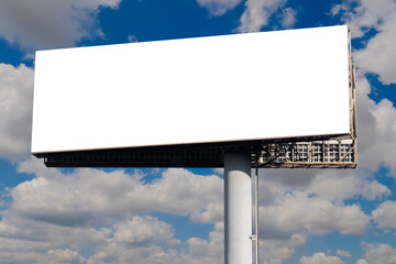Fototapeta premium Blank wide horizontal white billboard mockup or large display against the blue sky with white clouds. Consumerism, marketing, white screen, template, mock up and outdoor advertising concept