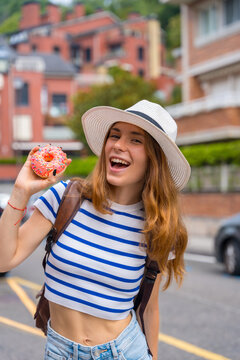 Young woman traveling enjoying a sweet donut outdoors