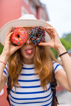 Young woman playfully covering eyes with colorful donuts