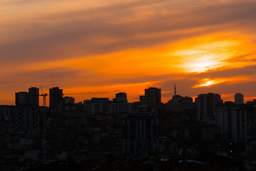 Fototapeta premium Dramatic sunset sky with the setting sun over the city of Istanbul, Turkey in the evening - apartment, residential buildings silhouettes. Summer, architecture, urban and cityscape concept
