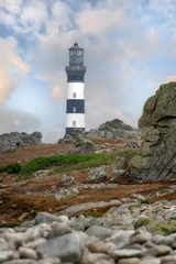 Vue verticale de la partie superieure du phare du creac'h sur l'ile d'ouessant en région bretagne, avec amat de galets et rochers au premier plan. © jmbreizh