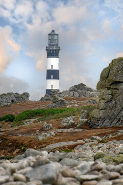 Vue verticale de la partie superieure du phare du creac'h sur l'ile d'ouessant en r&eacute;gion bretagne, avec amat de galets et rochers au premier plan.