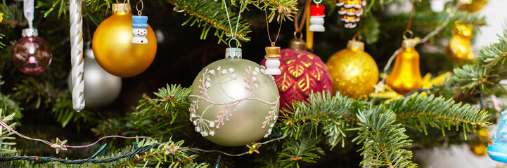 Obraz premium A Christmas tree stands with many colorful ornaments hanging from its branches. Each ornament shows different shapes and colors, celebrating the festive season and bringing joy to the home