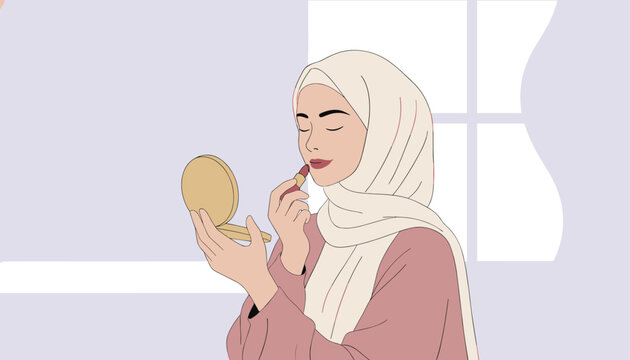 Beautiful young Muslim woman in a cream hijab applying lipstick while looking into a compact mirror near a window.