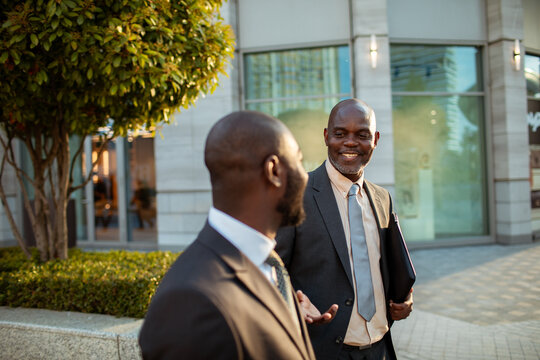 Two businessmen talking outside modern office building