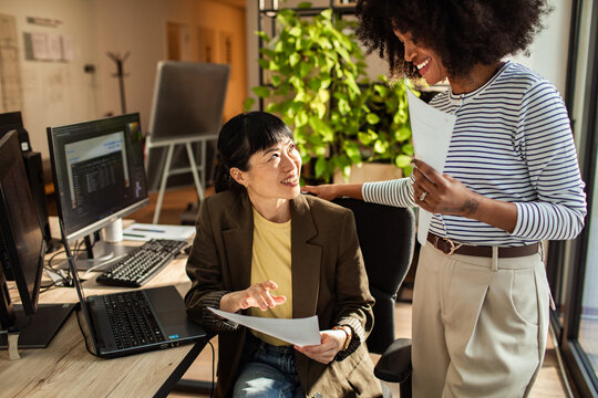 Two coworkers collaborating over documents in modern office