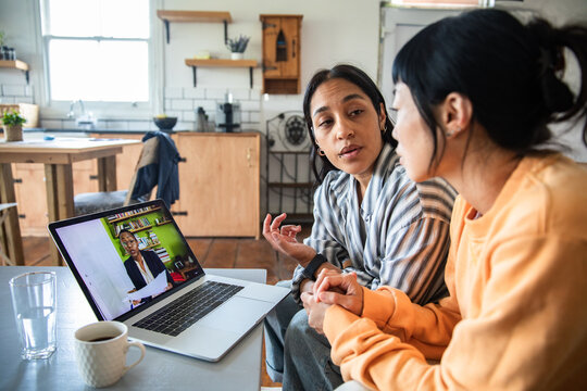 Two women having online consultation in home kitchen