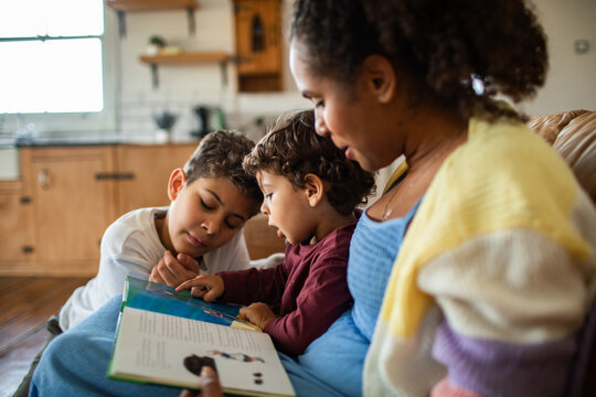 Mother and two children reading a picture book at home
