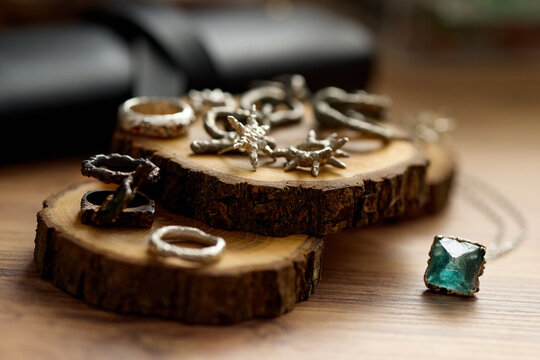 Close up of handmade rings and pendant displaying on wood slices, presenting artisan jewelry collection and product styling. Ideal for ecommerce banners, craft branding, gift marketing